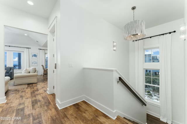 hall featuring baseboards, a wealth of natural light, and an upstairs landing