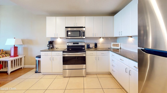 11800 Front Bch Unit 2-407, Panama City Beach, FL 32407 - kitchen featuring white cabinetry, light tile patterned floors, backsplash, dark stone counters, and appliances with stainless steel finishes