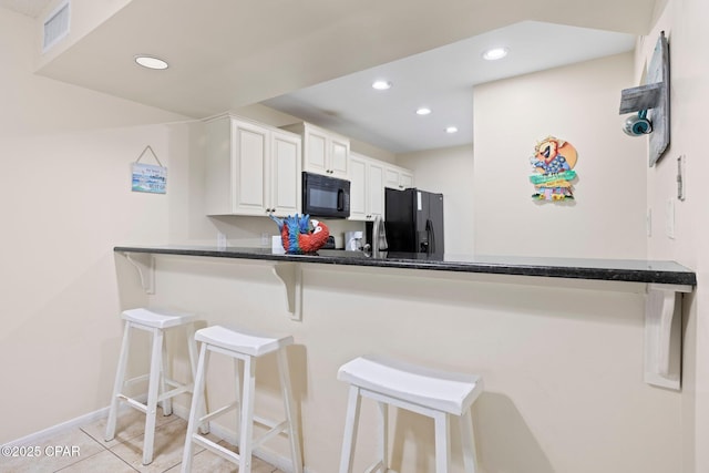 520 N Richard Jackson Blvd Unit 1804, Panama City Beach, FL 32407 - kitchen with black appliances, a peninsula, a breakfast bar, baseboards, and white cabinetry