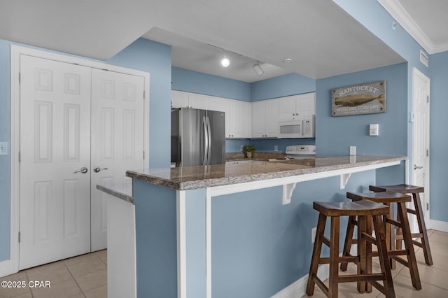 14701 Front Beach Rd Unit 2128, Panama City Beach, FL 32413 - kitchen featuring white appliances, light tile patterned floors, a peninsula, white cabinetry, and a breakfast bar