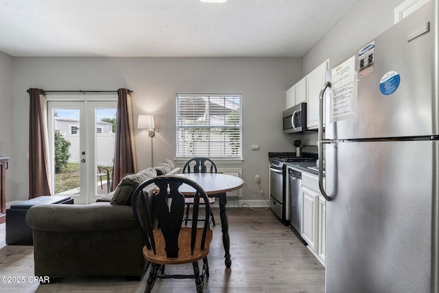 17878 Front Beach Rd Unit B2, Panama City Beach, FL 32413 - kitchen with white cabinetry, french doors, stainless steel appliances, baseboards, and wood finished floors