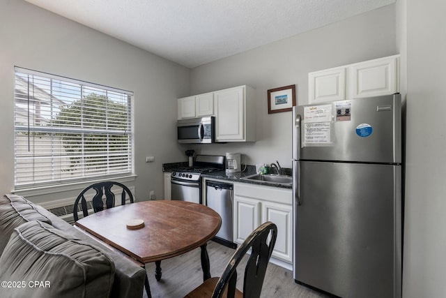 17878 Front Beach Rd Unit B2, Panama City Beach, FL 32413 - kitchen featuring light wood-style flooring, dark countertops, appliances with stainless steel finishes, white cabinetry, and a sink