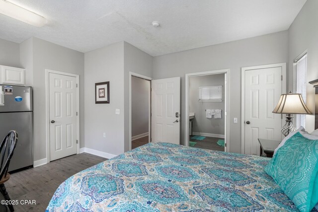 17878 Front Beach Rd Unit B2, Panama City Beach, FL 32413 - bedroom with a textured ceiling, baseboards, connected bathroom, dark wood-type flooring, and freestanding refrigerator