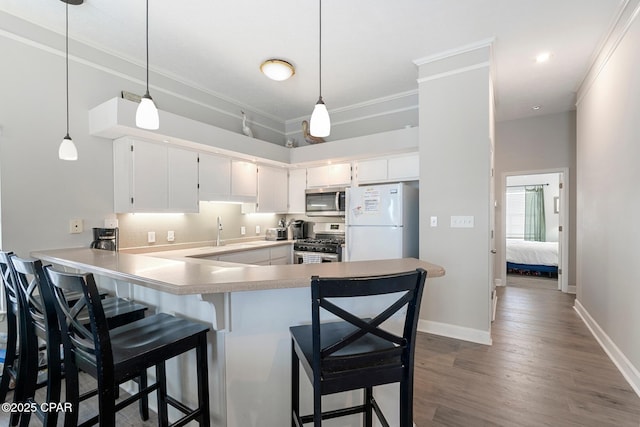 17878 Front Beach Rd Unit B2, Panama City Beach, FL 32413 - kitchen with light countertops, a peninsula, ornamental molding, wood finished floors, and appliances with stainless steel finishes