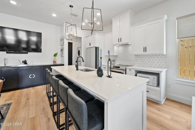 314 Tanaga St, Panama City Beach, FL 32413 - kitchen featuring appliances with stainless steel finishes, a sink, light wood finished floors, light stone counters, and decorative backsplash