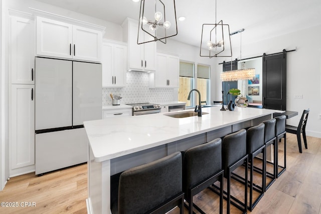 314 Tanaga St, Panama City Beach, FL 32413 - kitchen featuring white fridge, a sink, a chandelier, a kitchen island with sink, and white cabinets