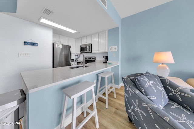 kitchen featuring white cabinets, appliances with stainless steel finishes, light wood-style floors, and visible vents