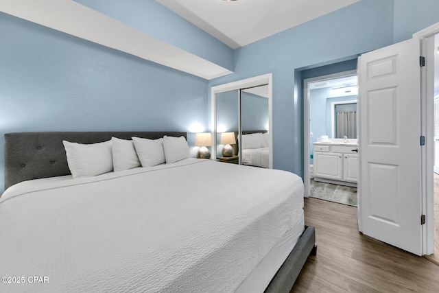 bedroom with a closet, ensuite bath, and wood finished floors