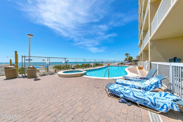 view of pool with a patio, fence, and a pool with connected hot tub
