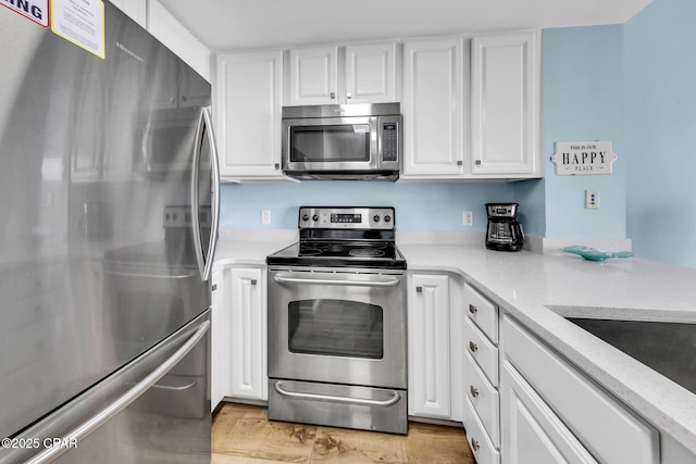 kitchen featuring white cabinets, light wood-style flooring, light stone countertops, and stainless steel appliances
