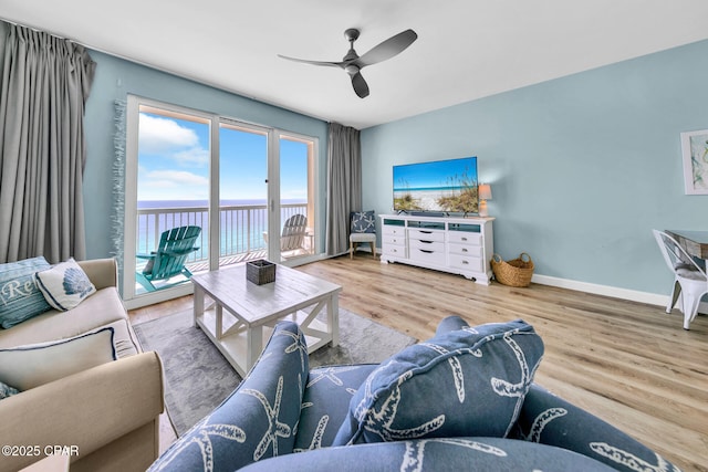 living area featuring baseboards, wood finished floors, and a ceiling fan