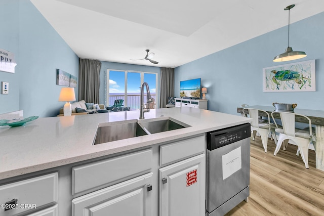 kitchen with white cabinets, a sink, light wood-style floors, open floor plan, and stainless steel dishwasher