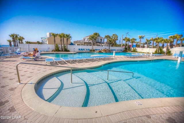 community pool with a patio and fence