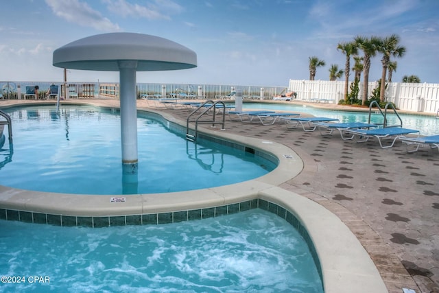 community pool with fence, a patio, and a hot tub