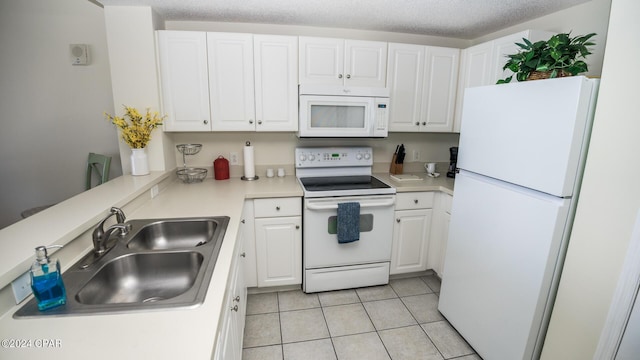 kitchen featuring white appliances, a sink, white cabinetry, light tile patterned floors, and light countertops