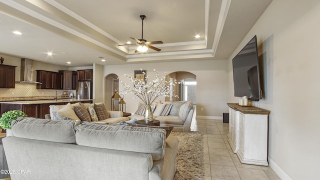 221 S Shoreview Dr, Panama City, FL 32404 - living area with arched walkways, a tray ceiling, a ceiling fan, light tile patterned floors, and ornamental molding