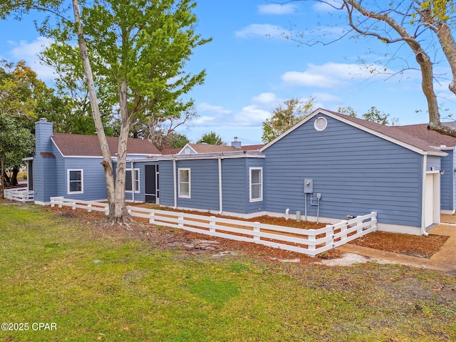 back of property with a lawn, fence, and a chimney