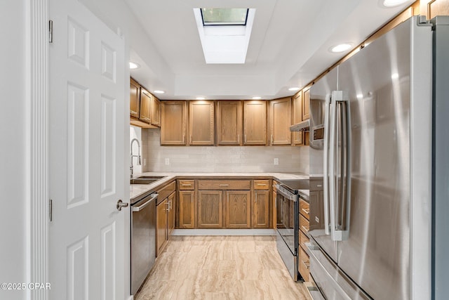 kitchen with brown cabinets, a sink, stainless steel appliances, under cabinet range hood, and marble finish floor