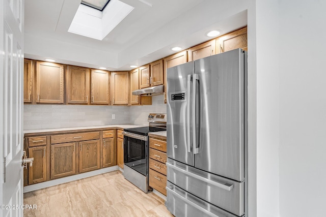 kitchen featuring under cabinet range hood, marble finish floor, light countertops, a skylight, and appliances with stainless steel finishes