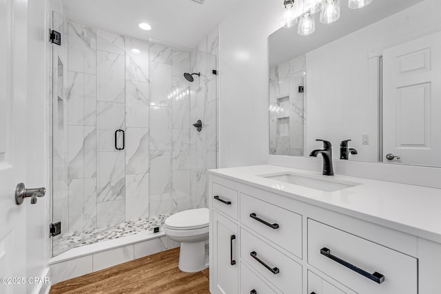 bathroom with recessed lighting, vanity, toilet, a marble finish shower, and wood finished floors
