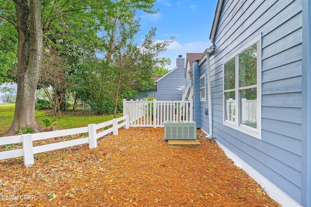 view of yard with central AC and fence