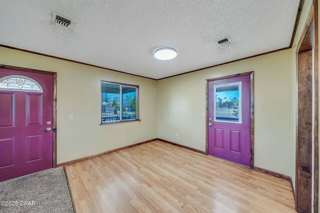 foyer entrance featuring a textured ceiling, visible vents, crown molding, and light wood finished floors