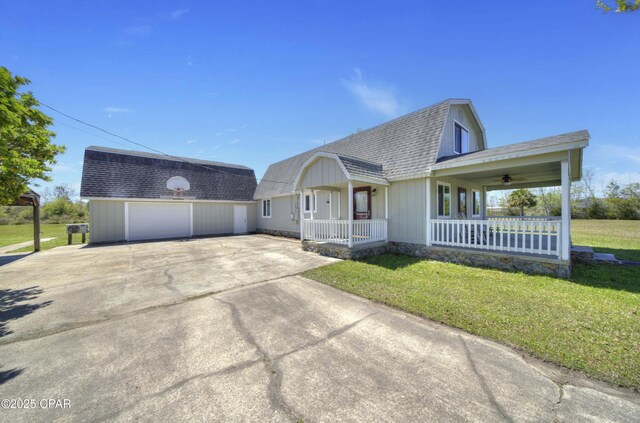 view of front of property featuring a gambrel roof, covered porch, roof with shingles, a front lawn, and a garage