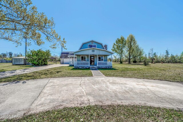 view of front of property featuring a gambrel roof, driveway, a front yard, a garage, and a porch
