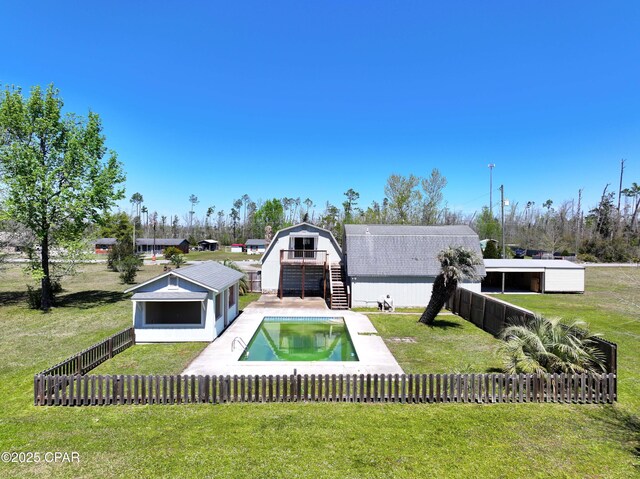 back of house with stairs, a fenced in pool, an outbuilding, fence private yard, and a lawn