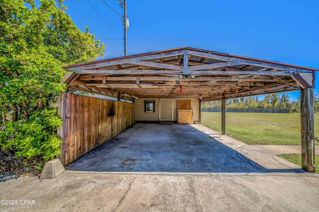 view of vehicle parking featuring a carport, fence, and concrete driveway