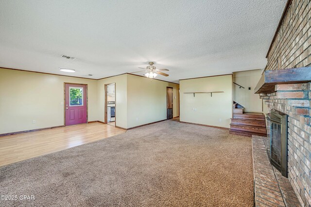 unfurnished living room with carpet flooring, a textured ceiling, visible vents, a fireplace, and a ceiling fan