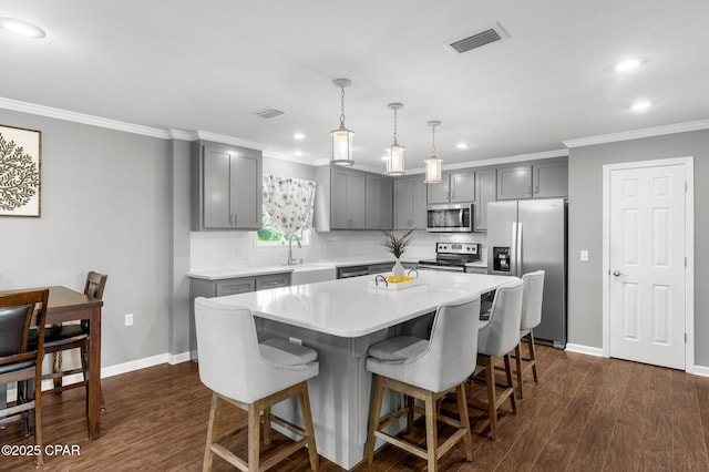 2187 Mayo Rd, Grand Ridge, FL 32442 - kitchen with stainless steel appliances, gray cabinetry, ornamental molding, a kitchen bar, and light countertops