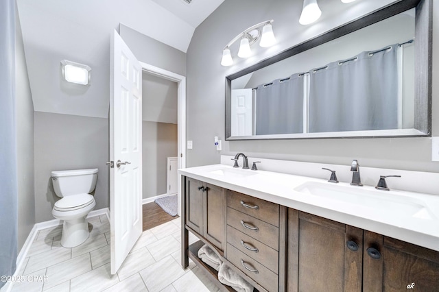 2187 Mayo Rd, Grand Ridge, FL 32442 - bathroom featuring double vanity, toilet, baseboards, and vaulted ceiling