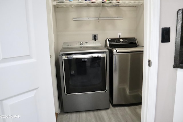 clothes washing area featuring separate washer and dryer and light wood finished floors