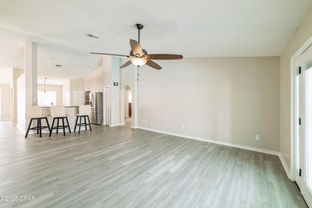unfurnished living room with light wood-style flooring, vaulted ceiling, visible vents, and plenty of natural light