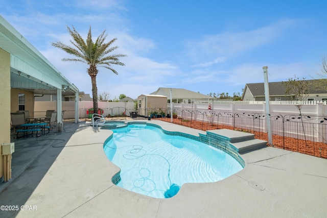view of swimming pool featuring a patio area, a pool with connected hot tub, a fenced backyard, an outdoor structure, and a storage unit