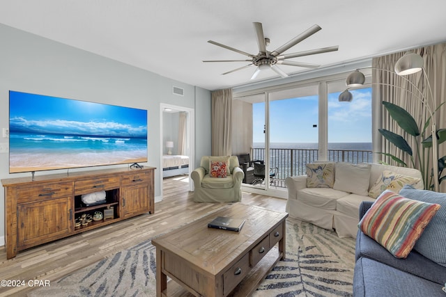 living room featuring a water view, visible vents, light wood-style floors, and ceiling fan