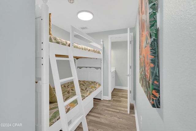 bedroom with baseboards, visible vents, and wood finished floors