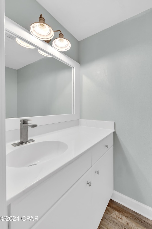 bathroom featuring baseboards, wood finished floors, and vanity