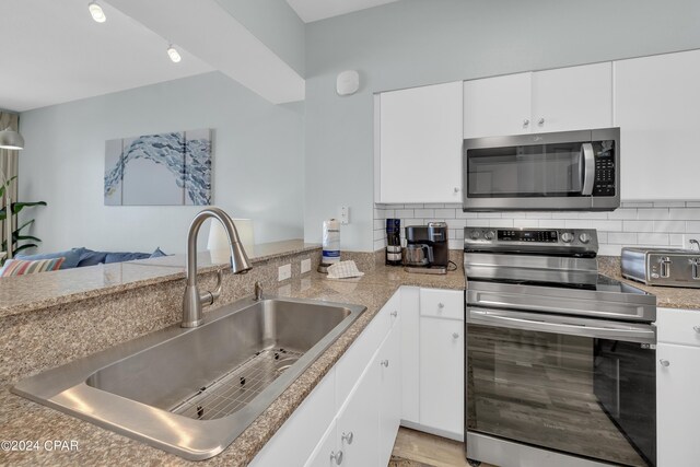 kitchen featuring white cabinetry, a sink, stainless steel appliances, and decorative backsplash