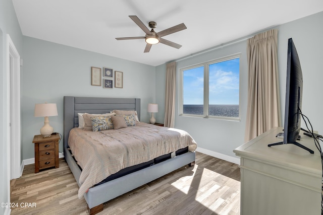 bedroom featuring baseboards, ceiling fan, and light wood-style flooring