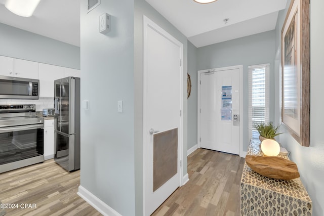 foyer with baseboards and light wood-style floors