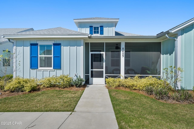 8453 Landshark Blvd, Panama City Beach, FL 32413 - exterior space with board and batten siding, a front lawn, a sunroom, and roof with shingles