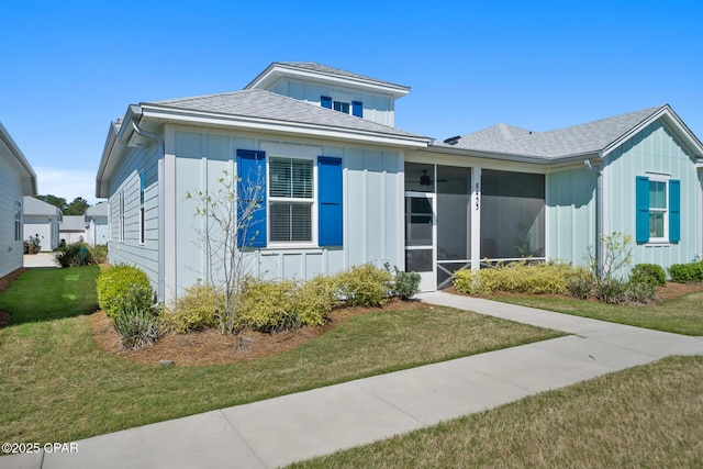 8453 Landshark Blvd, Panama City Beach, FL 32413 - view of front of home featuring a sunroom, roof with shingles, board and batten siding, and a front lawn