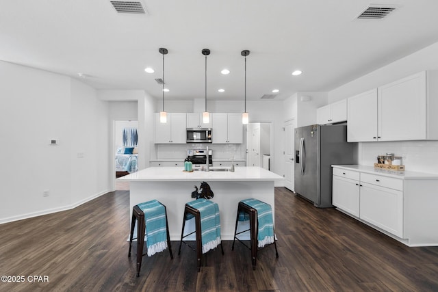 8453 Landshark Blvd, Panama City Beach, FL 32413 - kitchen with dark wood finished floors, visible vents, a breakfast bar, and appliances with stainless steel finishes