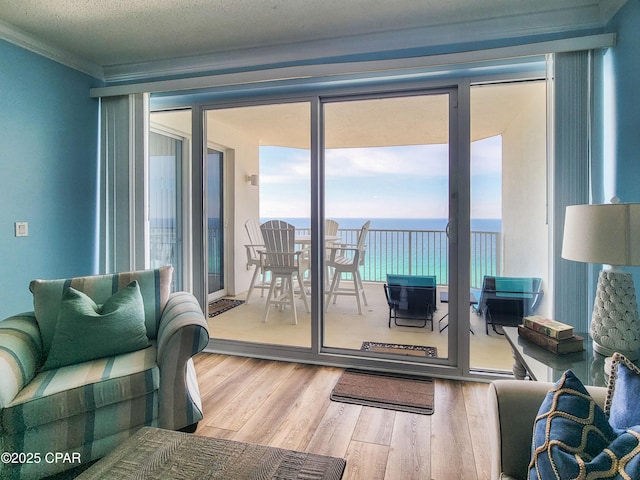 living room featuring wood finished floors, a water view, and crown molding