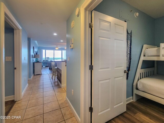 hallway featuring baseboards, recessed lighting, and light tile patterned floors