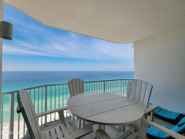 balcony with view of water and beach and outdoor dining area