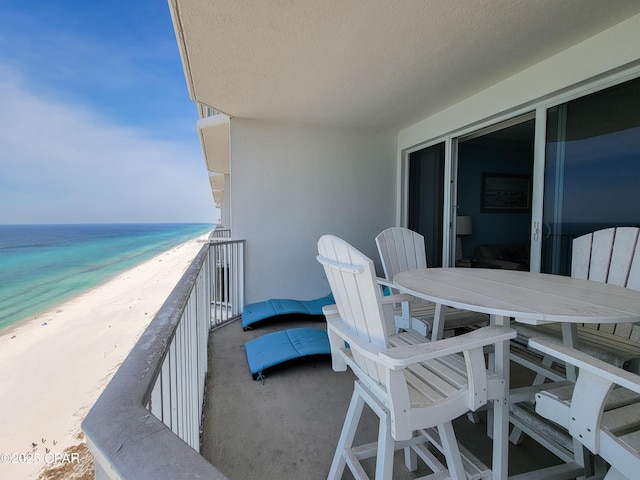 balcony featuring view of water and beach and outdoor dining space