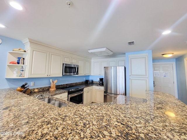 kitchen featuring stainless steel appliances, dark stone countertops, a sink, open shelves, and white cabinetry